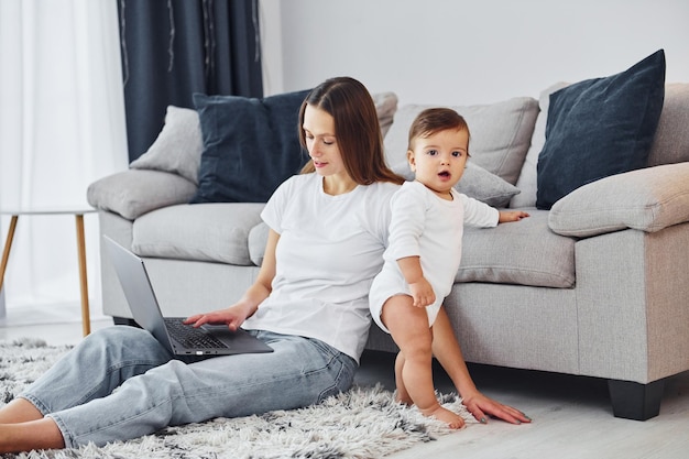 Laptop de cor prata mãe com sua filha está dentro de casa juntos