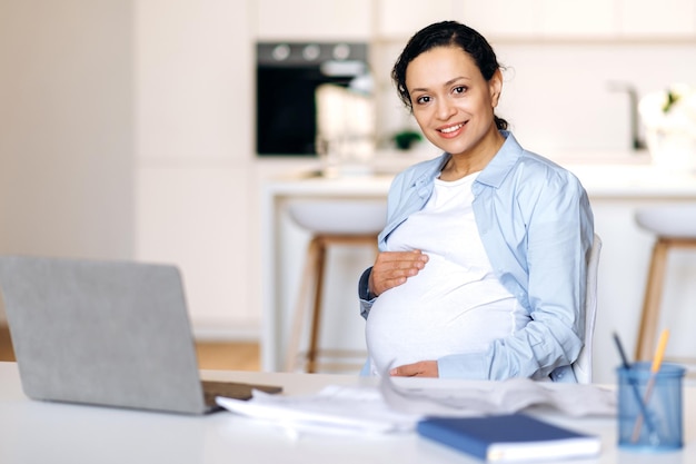 Foto laptop de gerente de mulher de raça mista grávida feliz