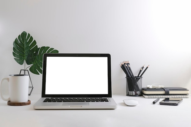 Laptop de maquete com livros de xícara de café de exibição vazia e porta-retrato na mesa brancax9