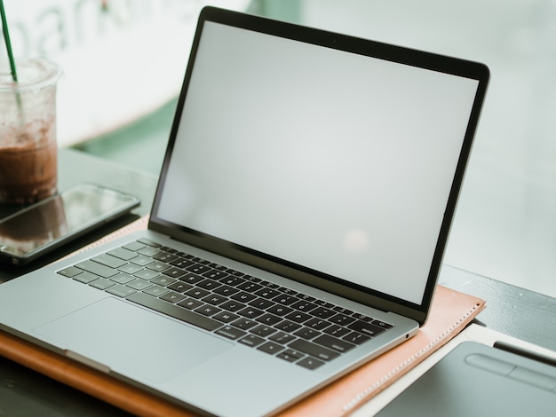 Laptop des leeren Bildschirms mit Kamera- und Eiskaffee im Café.