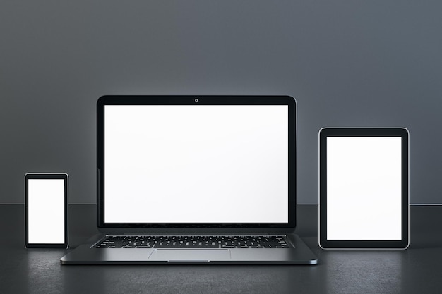 Laptop, digitaler Tablet und Smartphone mit leerem weißen Bildschirm auf einem Betontisch Technologie- und Kommunikationskonzept 3D-Rendering