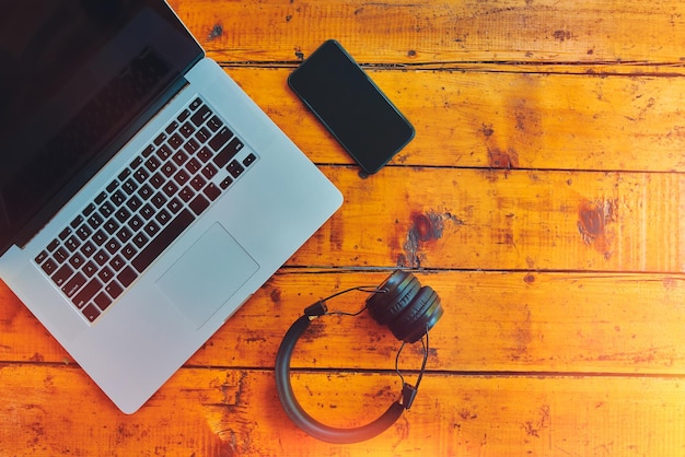 Foto laptop, drahtlose kopfhörer und smartphone auf einem holztisch, freiberufler, arbeitsfläche, moderne geräte