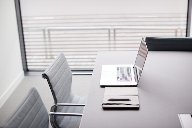 Laptop e notebook na mesa na sala de reuniões vazia do escritório moderno