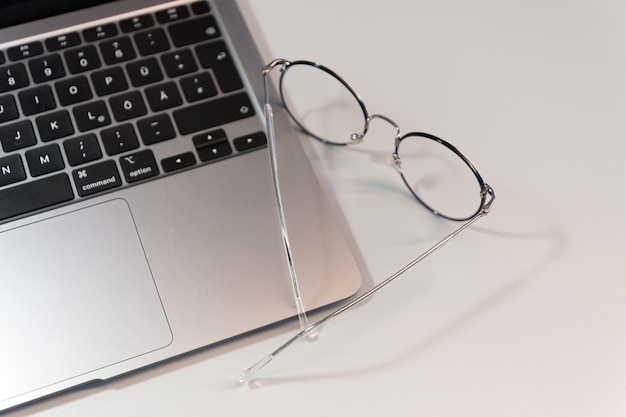 Laptop e óculos em um fundo cinzento