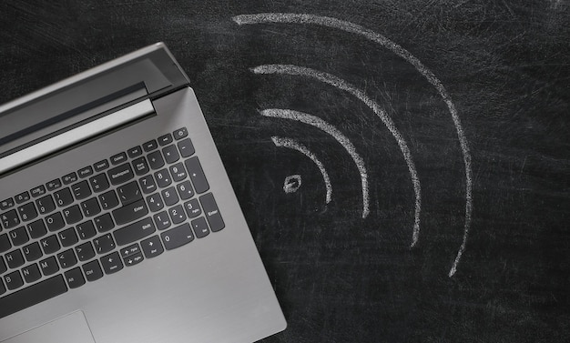 Laptop e símbolo wi-fi giz desenhado à mão no quadro-negro