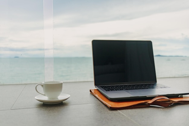 Laptop e xícara de café na varanda do hotel com vista para o mar funcionam do hotel