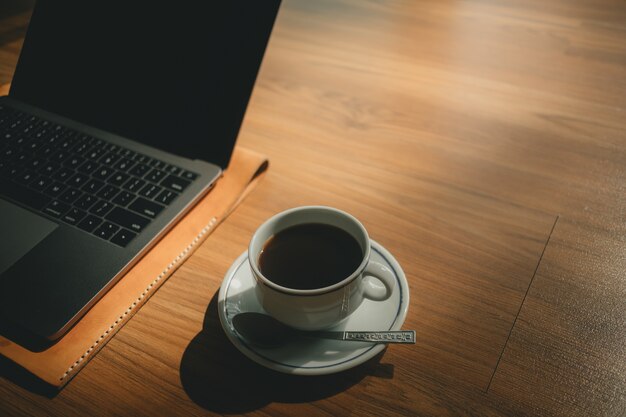 Laptop e xícara de café no chão de madeira