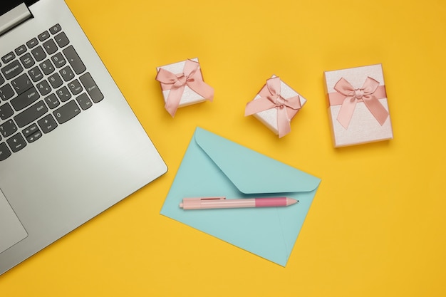 Laptop, envelope e caixas de presentes em fundo amarelo. Natal, dia dos namorados, aniversário. Vista do topo