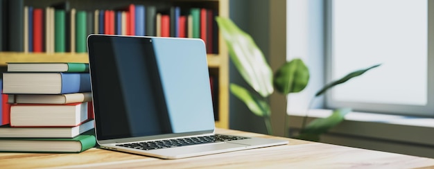 Laptop en un escritorio de madera con una pila de libros en una sala de biblioteca moderna Renderización 3D