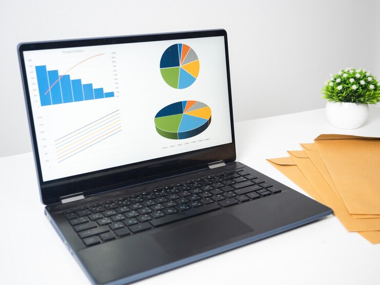 Foto laptop gráficos gráficos negocios en pantalla con documento en el espacio de copia de mesa