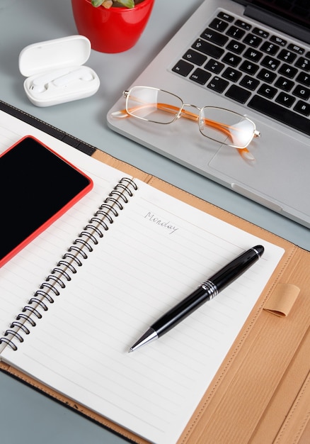 Laptop, Handy und geöffnete Agenda auf einem grauen Schreibtisch hautnah. Geschäftskonzept