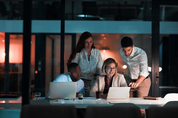 Laptop de investigación y gente de negocios en la oficina por la noche con gráficos de la bolsa de valores para la inversión corporativa Discusión computadora y asesores financieros trabajando en el informe de ganancias de la compañía con fecha límite