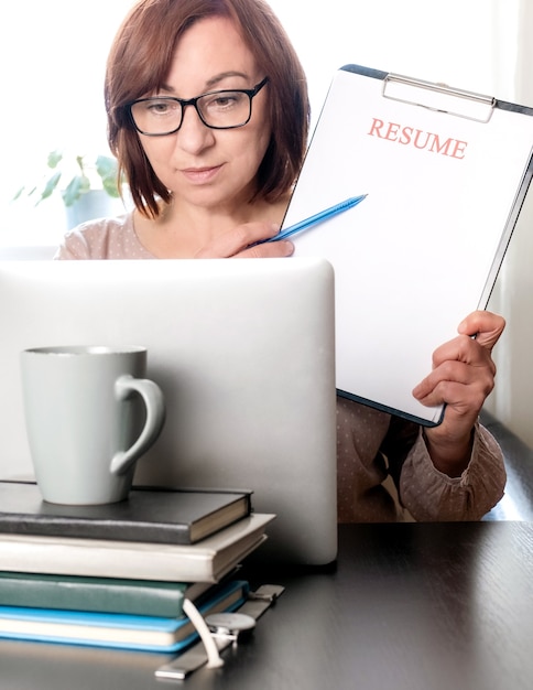 Laptop Lebenslauf halten Frau mittleren Alters 50 plus Arbeitsplatz leere Lebenslauf Blatt Anwendung