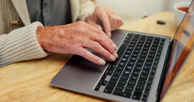 Laptop mecanografiado o manos de un hombre mayor para comunicación de telemedicina o consulta en línea en el hogar Tecnología o lectura en la mesa para personas mayores de sexo masculino para investigación de atención médica o información médica