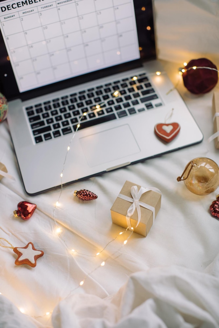 Foto laptop mit dezember-kalender auf dem bildschirm weihnachtsdekorationen geschenkkiste lichter auf weißem leinen