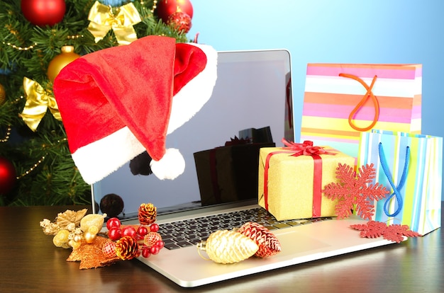 Laptop mit Geschenken auf dem Tisch auf blauem Hintergrund