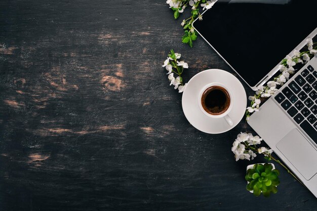 Laptop mit Kaffee und Blumen Geschäft auf einem hölzernen Hintergrund Ansicht von oben Kopieren Sie Platz