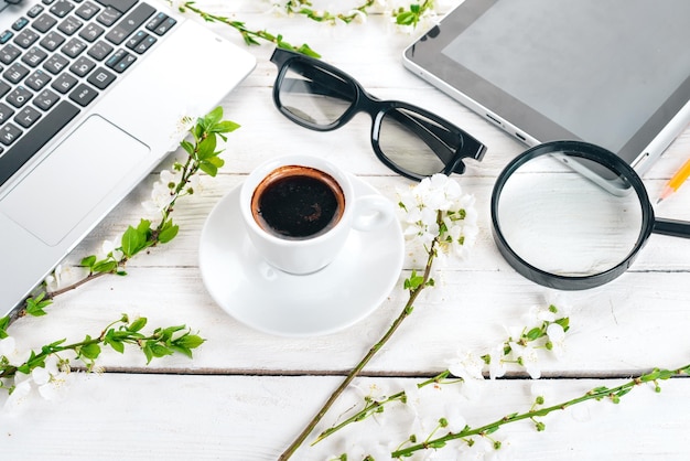 Laptop mit Kaffee und Blumen. Geschäft. Auf einem hölzernen Hintergrund. Ansicht von oben. Platz kopieren.