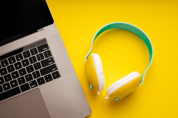 Laptop mit Kopfhörern auf gelbem Hintergrund DJ-Spielunterhaltung oder Freizeitkonzept