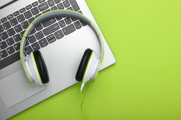 Laptop mit Kopfhörern auf grüner Oberfläche