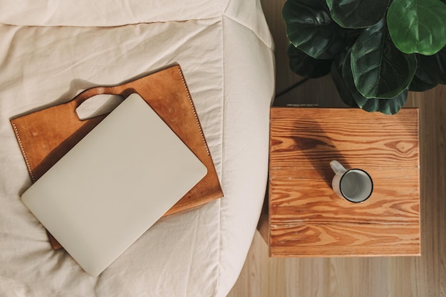 Laptop mit Lederhülle auf beigem Sofa im Wohnzimmer