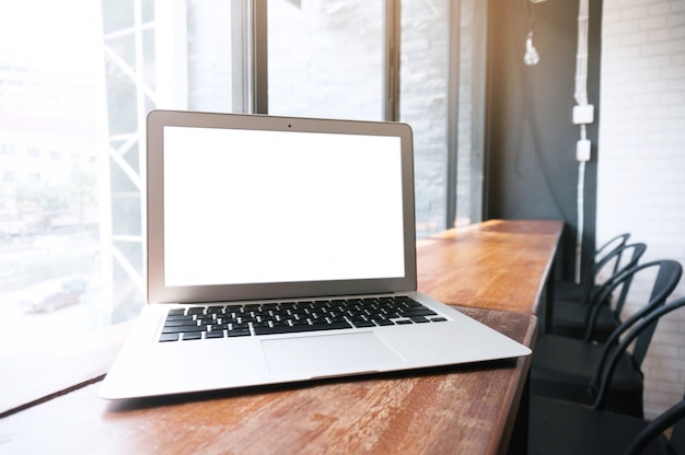 Laptop mit leeren Bildschirm auf Holztisch vor Büro Fenster.