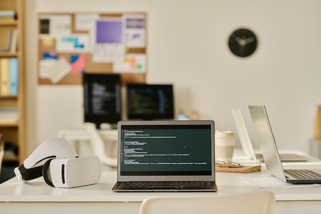Foto laptop mit programmcode auf dem bildschirm auf dem tisch im büro