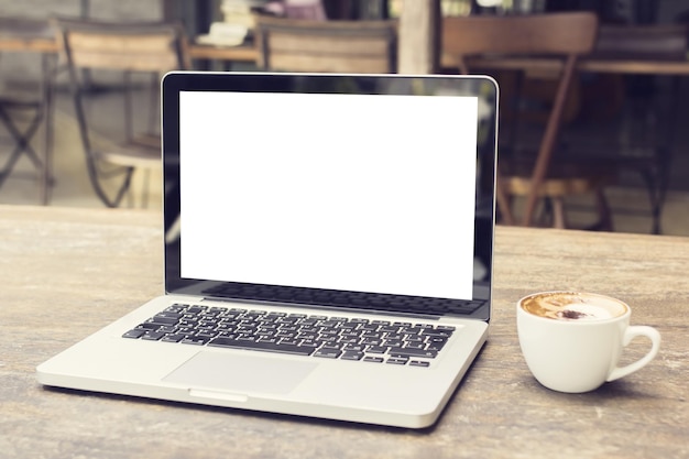 Laptop mit weißem Bildschirm auf einem Tisch in einem Café-Attrappe