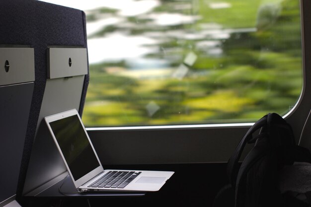 Foto laptop y mochila junto a la ventana en el tren