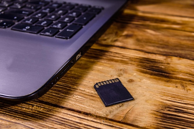 Laptop moderno e cartão de memória SD em uma mesa de madeira