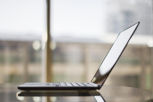 Laptop moderno em uma mesa de vidro em casa