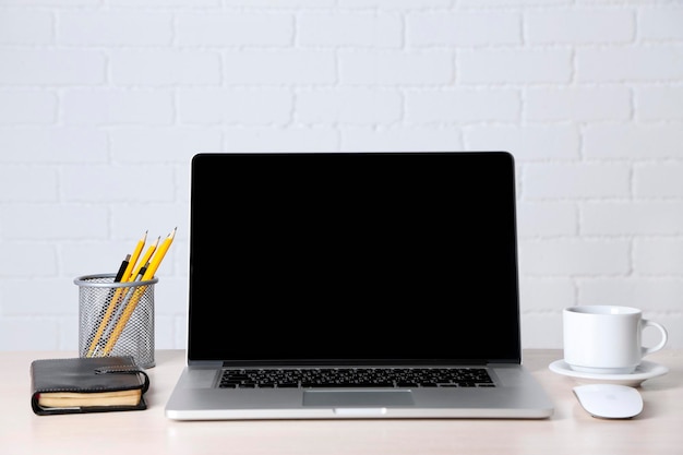 Laptop moderno en la mesa con fondo blanco en la pared