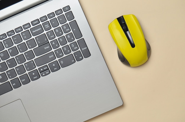 Laptop moderno, mouse sem fio sobre um fundo amarelo pastel, minimalismo, vista superior, configuração plana