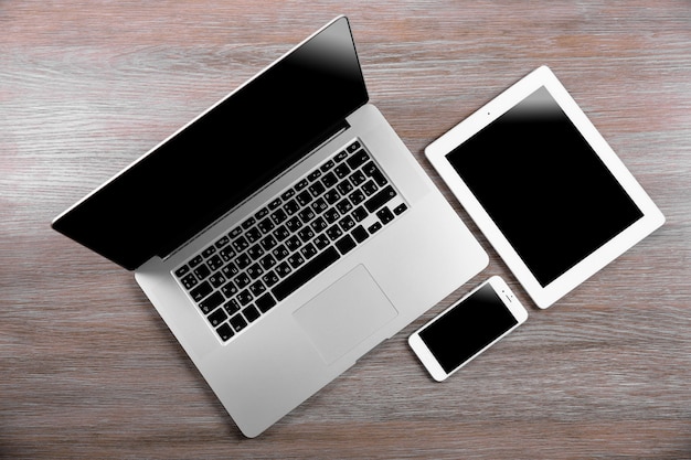 Laptop moderno, smartphone e tablet em uma mesa de madeira