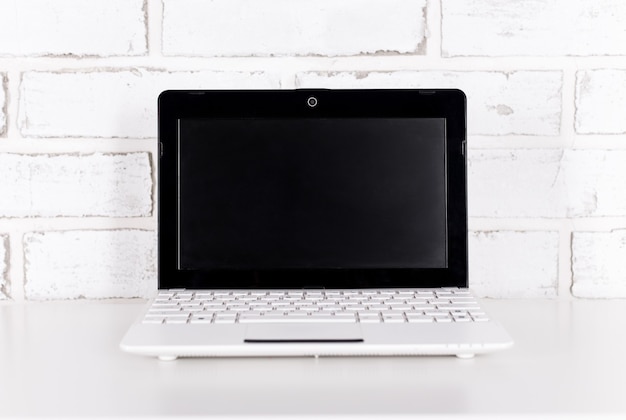 Laptop moderno sobre fundo de parede de tijolo branco