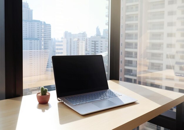 Laptop na mesa contra as janelas