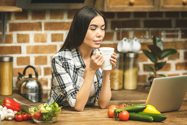 Laptop na mesa da cozinha e cozinha garota. relaxante