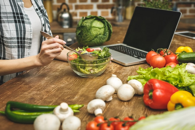 Laptop na mesa da cozinha e cozinha garota.