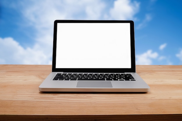 Foto laptop na mesa de madeira com fundo do céu azul