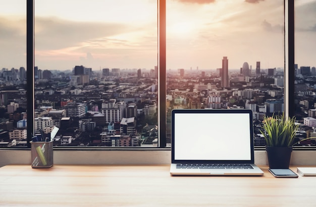 Laptop na mesa na sala de escritório no fundo da cidade de janela