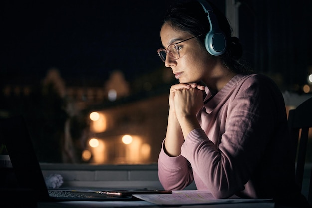 Laptop-Nacht und Musik mit einer Studentin in ihrem Haus, um Bildung oder Entwicklung über das Internet zu lernen Computerforschung und E-Learning mit einer Schülerin, die spät in einem dunklen Haus studiert