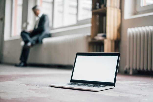 Laptop no chão com o empresário ao fundo