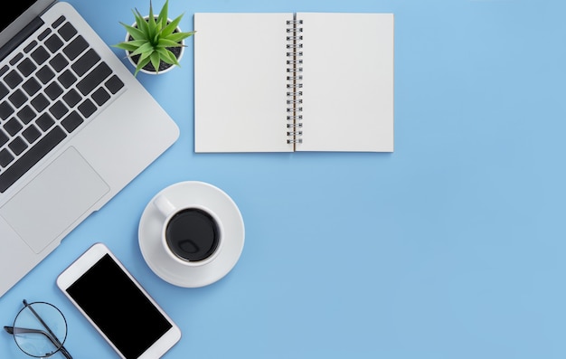 Laptop, notebook, smartphone e uma mão pegando uma xícara de café em um fundo azul claro