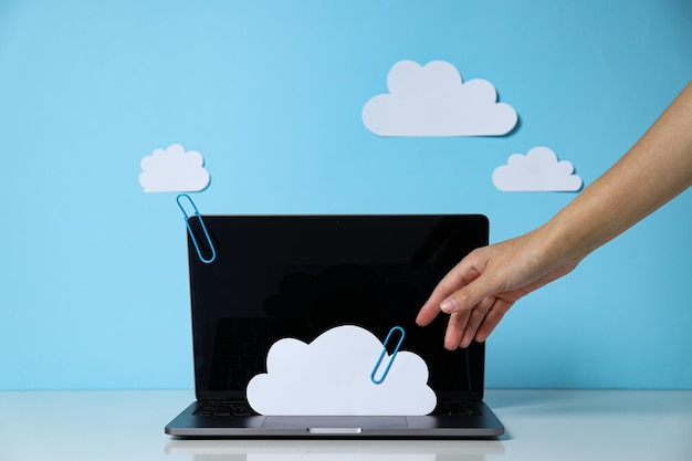 Laptop con nubes de papel en un fondo azul