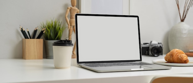 Laptop con pantalla blanca y un croissant