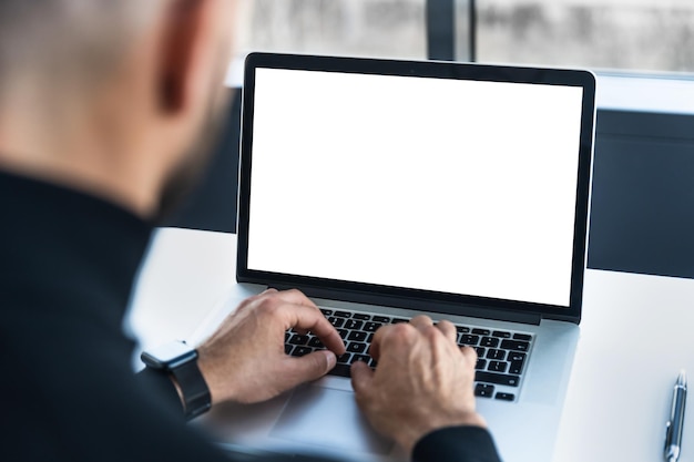 Foto laptop con pantalla blanca detrás de la cual trabaja la persona