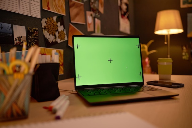 Laptop con pantalla verde en el escritorio en un espacio de trabajo acogedor