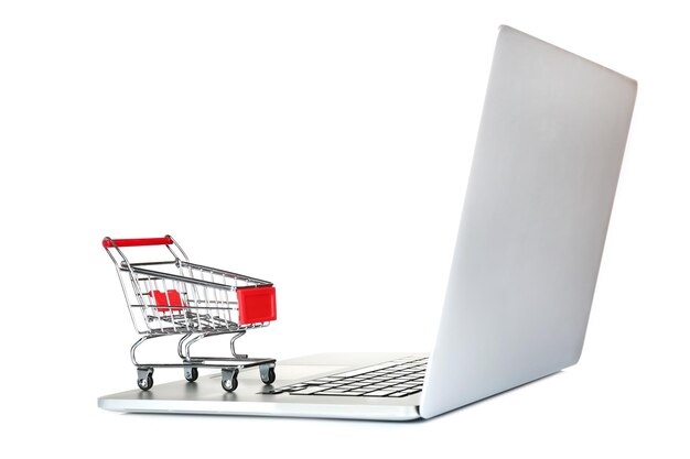 Laptop con un pequeño carrito de compras aislado sobre un fondo blanco