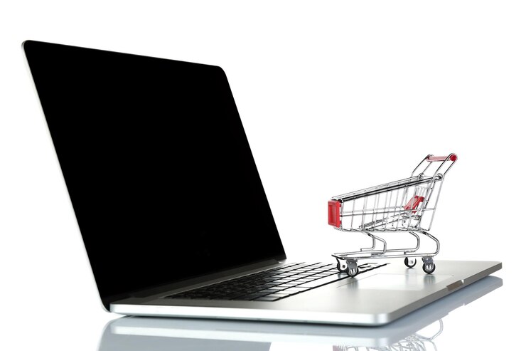 Foto laptop con un pequeño carrito de compras aislado sobre un fondo blanco