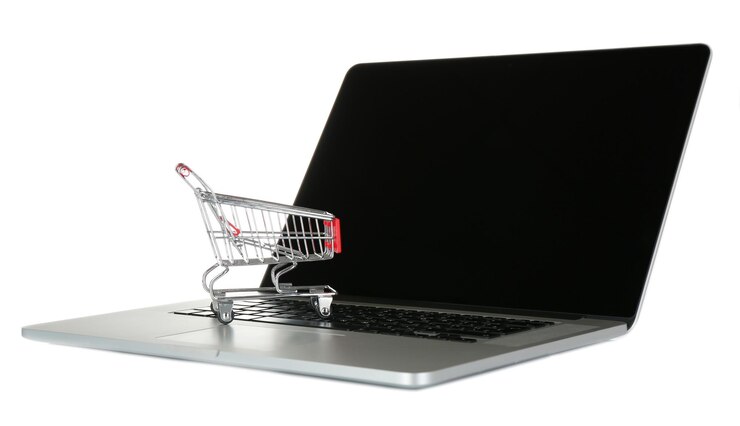 Foto laptop con un pequeño carrito de compras aislado sobre un fondo blanco